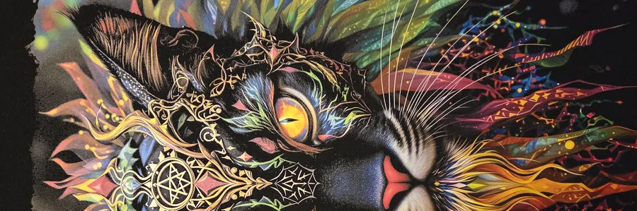 Détail large d’un transfert DTF sur chandail noir : les yeux jaunes d’un chat orné, entourés d’entrelacs dorés et de plumes multicolores.